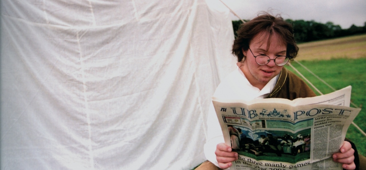 Tobias Wolf sitzt vor einer weißen Hütte und liest Zeitung