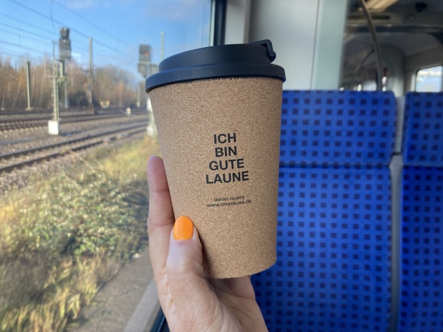 Ein Kaffeebecher mit Korkummantelung mit dem zentriert gesetzten Zitat ICH BIN GUTE LAUNE